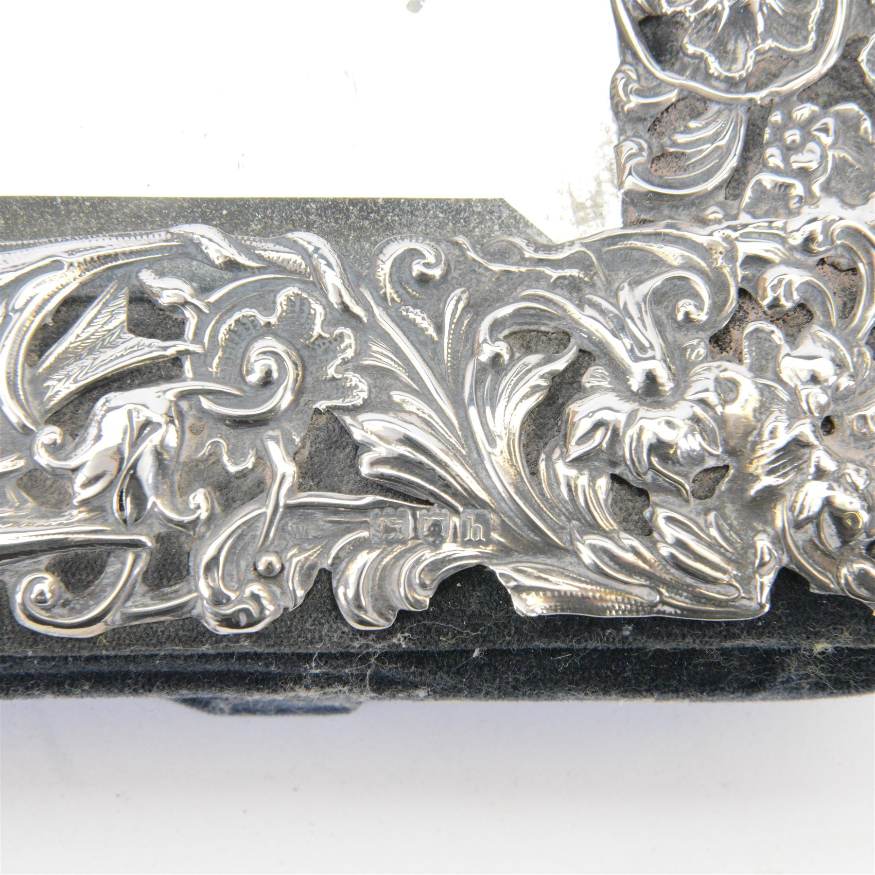 Edwardian silver mounted dressing table mirror, the bevelled mirror plate with silver surround embossed with flowers, C scrolls, putti and birds, with velvet easel support verso, hallmarked London 1903, maker's mark WC, probably for William Comyns & Sons, H33cm