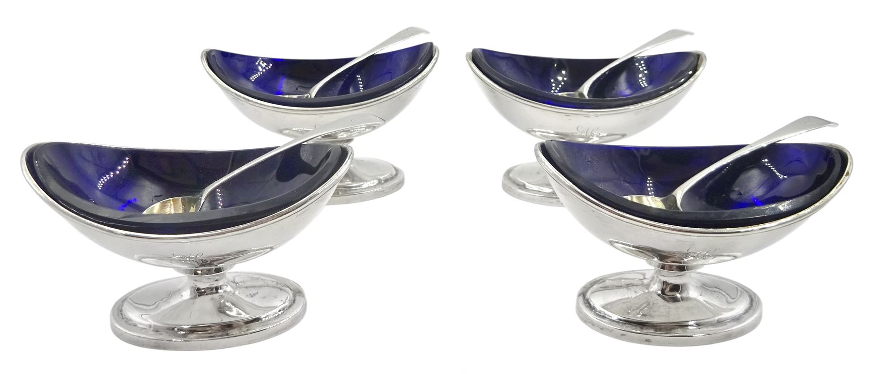 Set of four George III silver pedestal table salts, of navette form with gilt interiors and blue glass liners, hallmarked Solomon Hougham, London 1802 and 1803, together with a set of four George III Old English pattern salt spoons with gilt bowls, hallmarked London 1797, maker's mark WS, salts H6.5cm L10cm, gross weight exclusive of liners 11.51 ozt (358 grams)