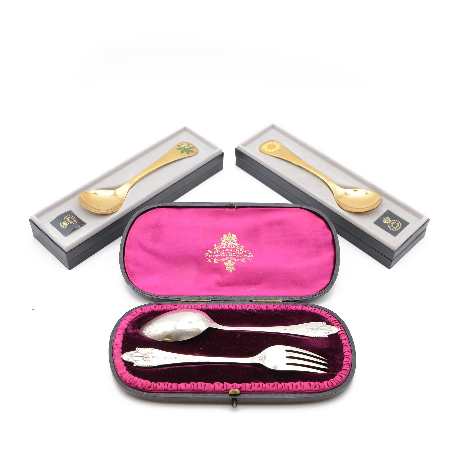 1920s Danish silver spoon and fork set by Georg Jensen, stamped 925S Georg Jensen, with import marks for London 1926, contained within fitted tooled leather retailers case, together with two Georg Jensen silver-gilt year spoons, comprising 1975 example with enamel woodruff flower decoration, with personal inscription verso and a 1973 example with enamel marigold decoration, both boxed