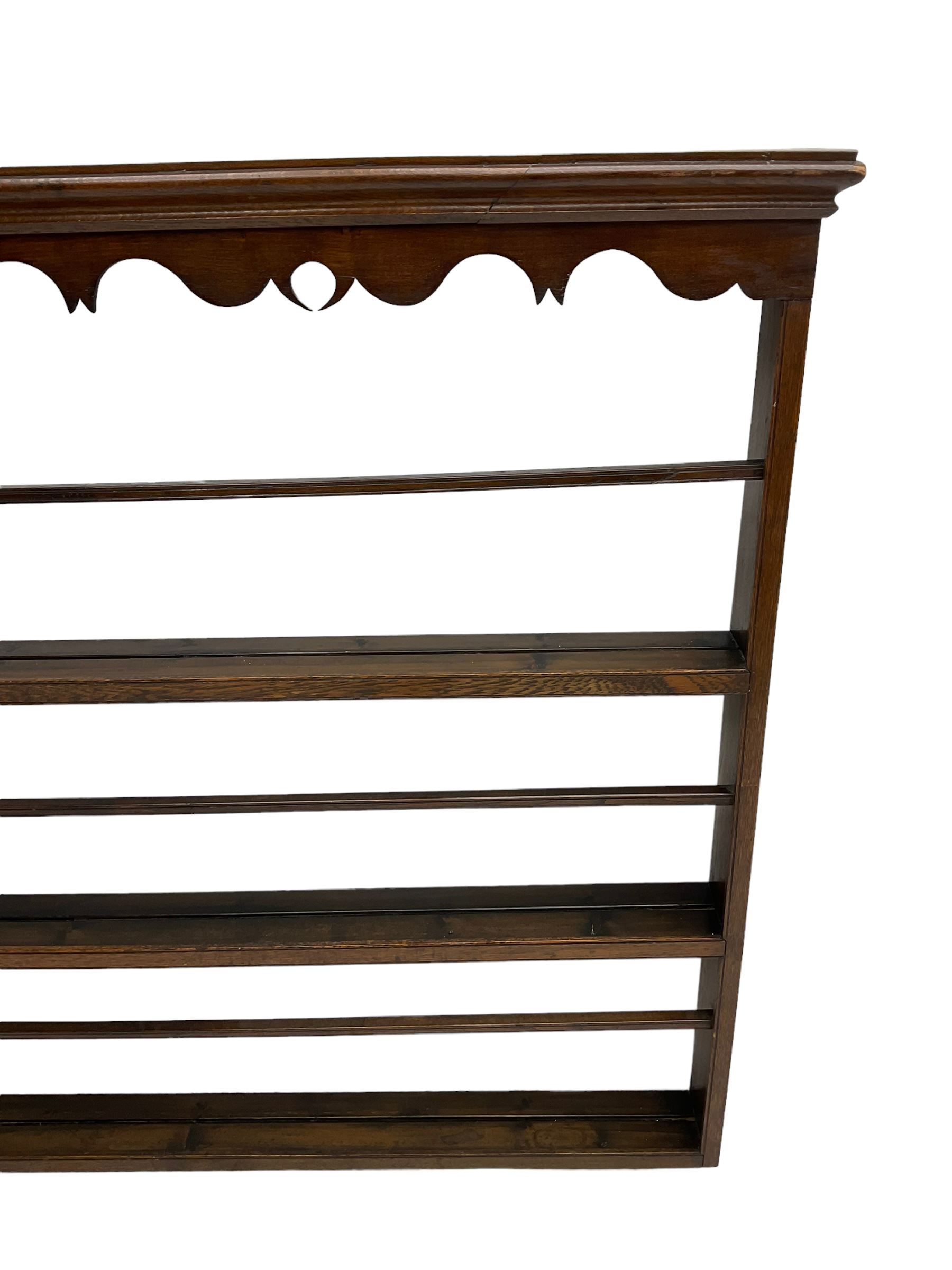 20th century oak wall hanging plate rack, shaped fretwork frieze over three tiers
