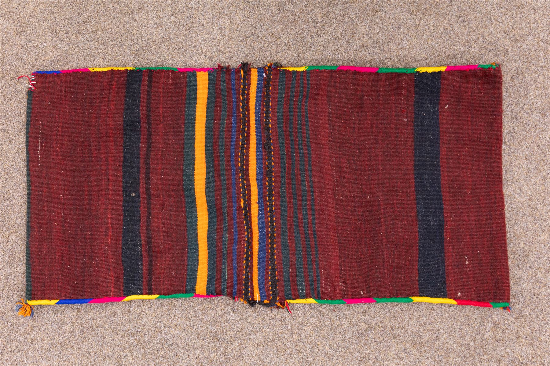 South West Persian Qashgai saddlebag, (Khorjin) saddlebag, comprising two pile-woven panels joined by a flatweave underside, each decorated with madder-red field filled stylized geometric motifs and hooked devices, enclosed by contrasting ivory borders populated with tribal figures and abstract forms