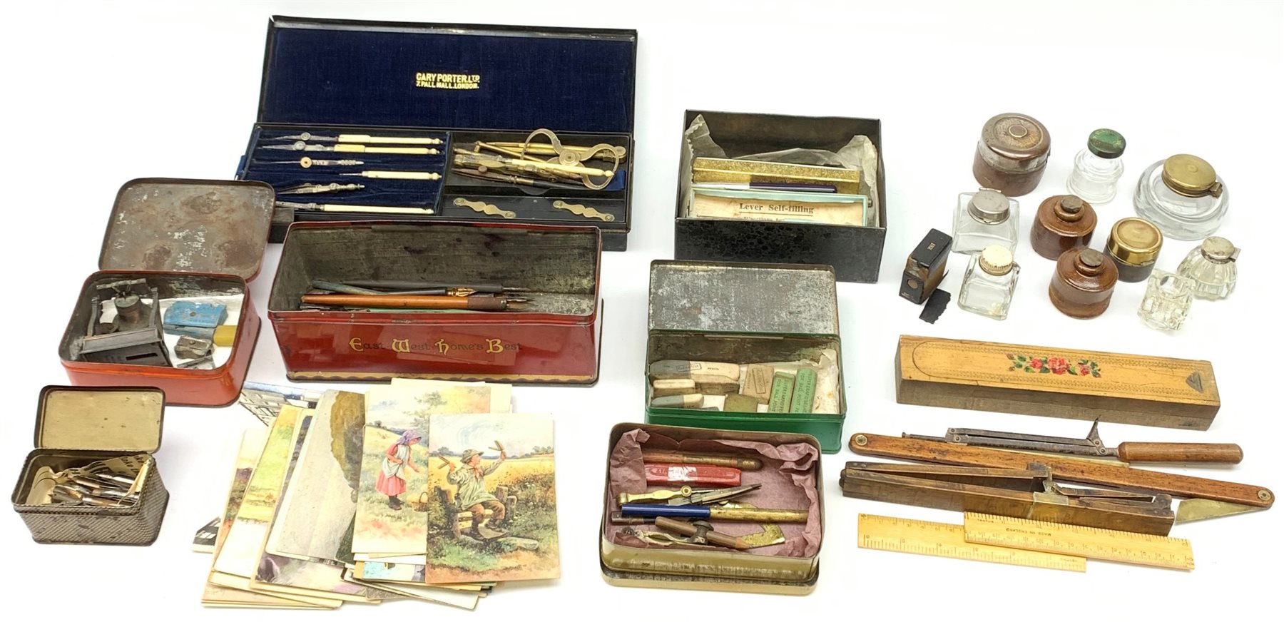 A selection of various writing accessories, to include a cased drawing instruments set, containging various dividers, compasses, and a folding rule, the case makred Cary Porter Ltd 7 Pall Mall London, a quantity of pen nibs, assorted inkwells, rubbers, and pens, etc., together with a selection of approximately forty postcards, to include a silk example. 