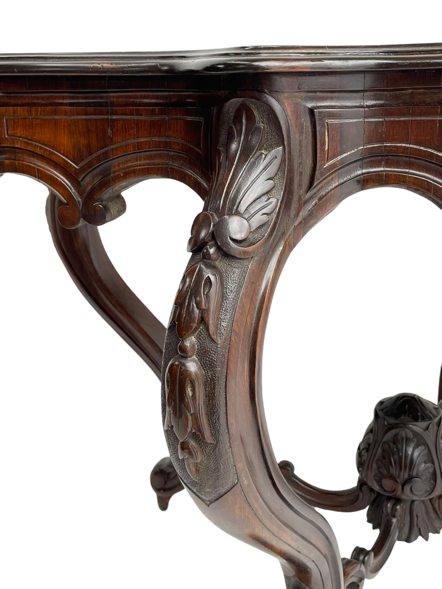 19th century Irish rosewood centre table, the shaped and moulded top over shaped apron carved with scrolled foliage, on serpentine supports carved with bell flowers, the supports united by anthemion carved finial and s-scroll x-framed stretchers