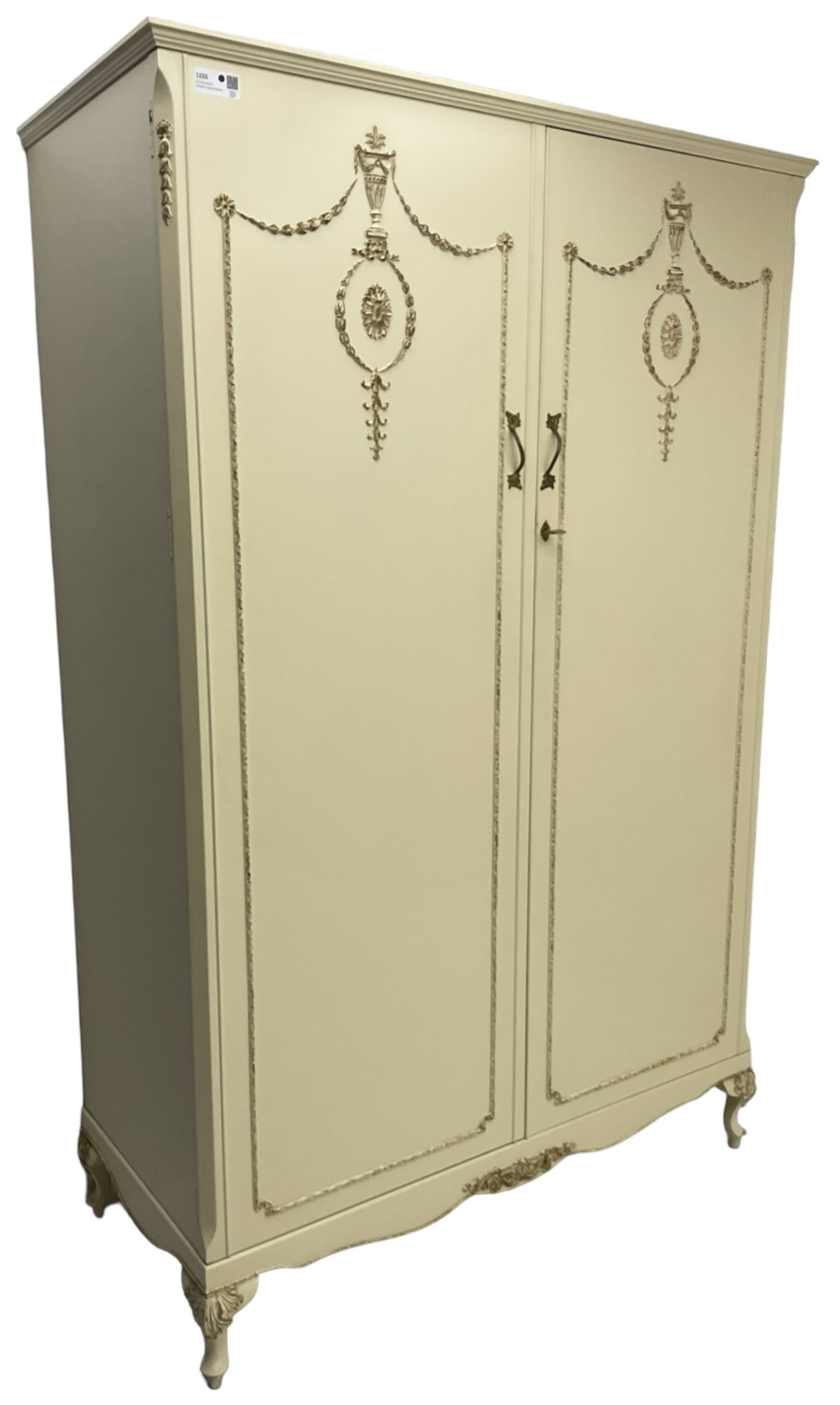 French classic design cream painted double wardrobe, the doors decorated with gilt and cream applied urn motifs with extending bell-flower festoons and ribbon twists, enclosing shelf and hanging rail, shaped apron on acanthus cabriole feet