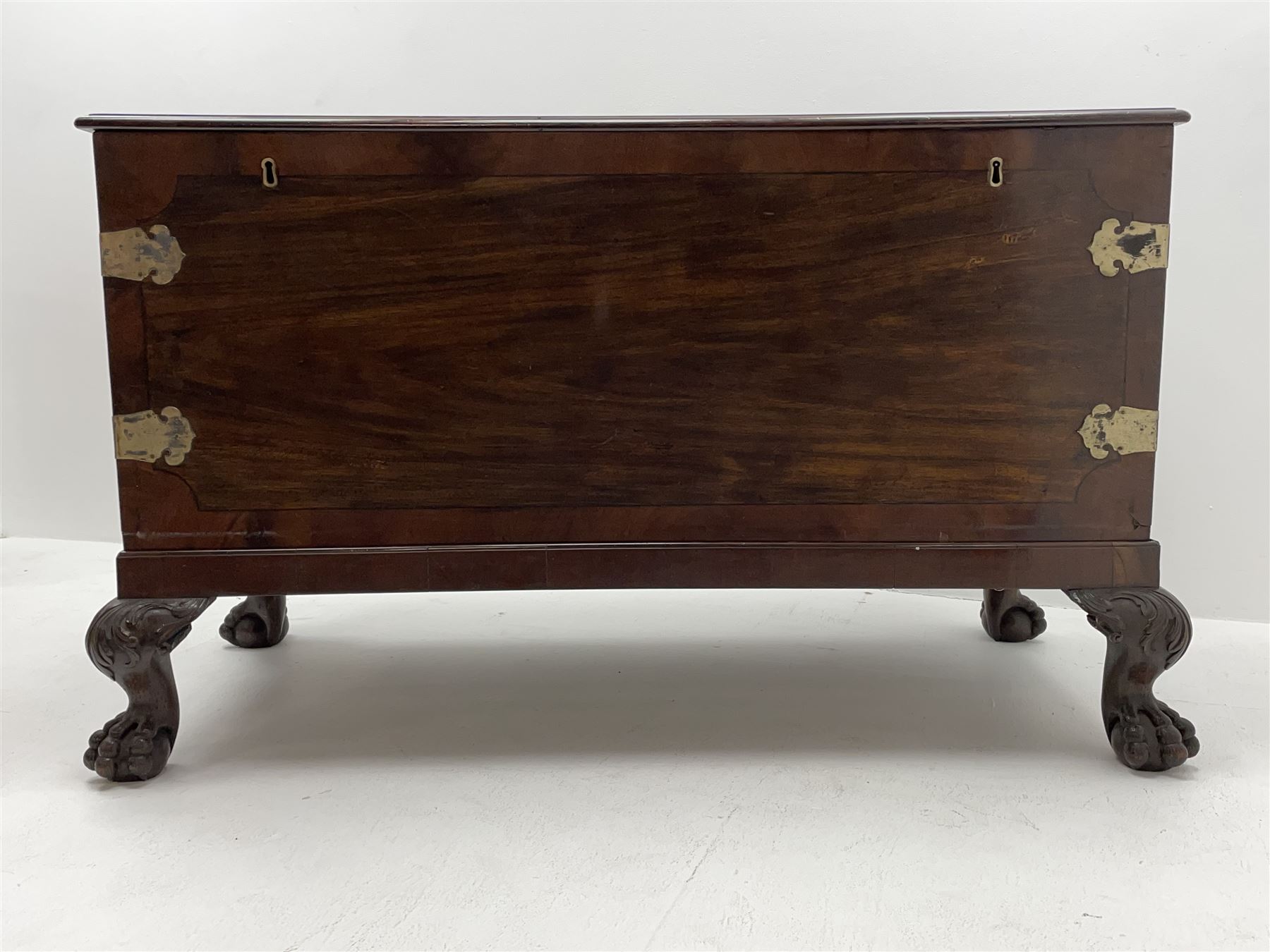 19th century camphor wood and mahogany silver chest, the hinged banded top with circular brass mounts which secure the interior strap hinges, fretwork metal strapping to the corners, on stand with plain frieze and acanthus carved cabriole ball and claw feet