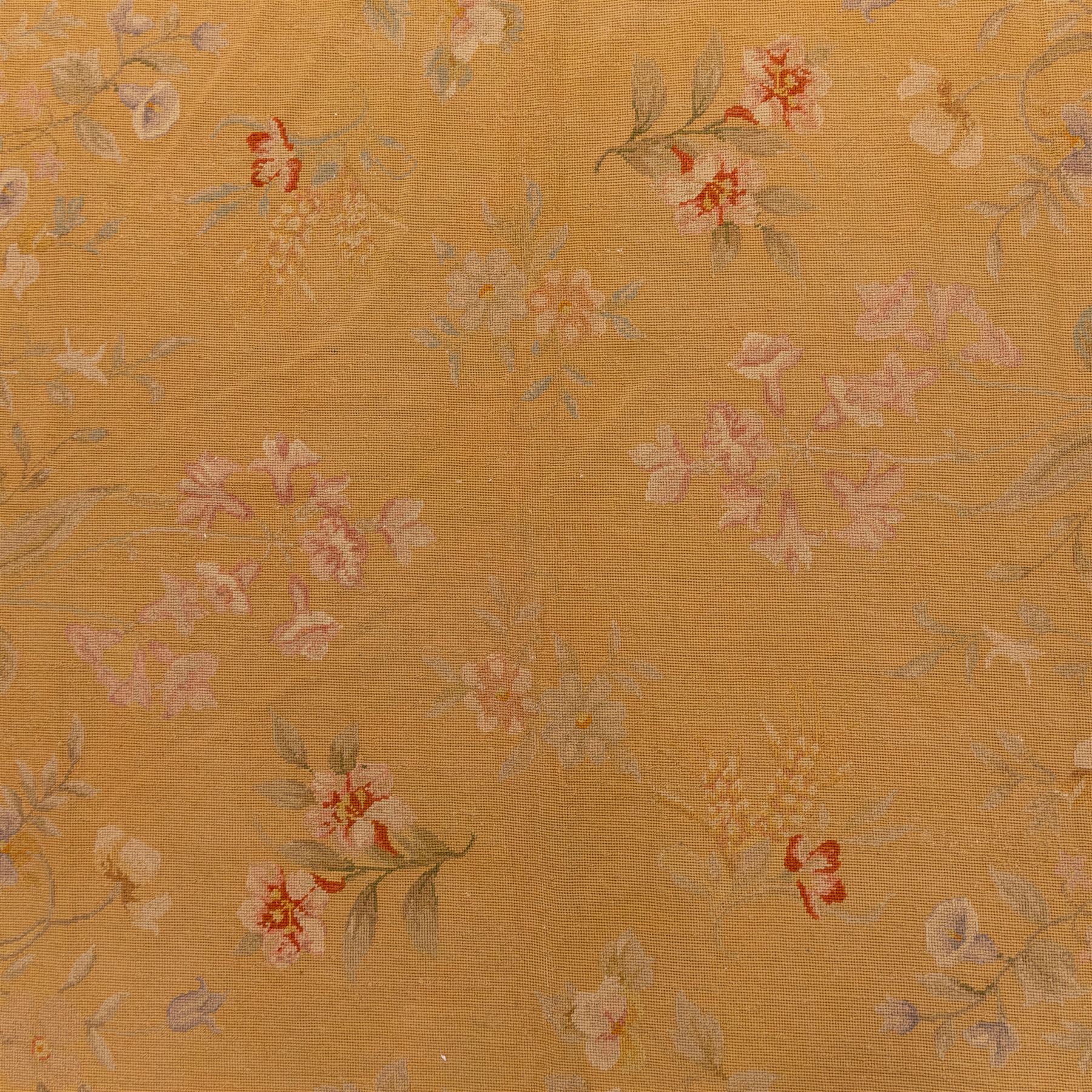 20th-century Aubusson-style woven tapestry of rectangular form with mustard yellow field decorated with scattered floral sprays in soft pastel tones of pink, cream, and muted green, within a narrow guard stripe with an outer border of trailing blossoms and foliage 