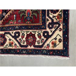 Persian Hamadan rug, the red ground field decorated with two floral medallions and stylised flower heads, repeating guarded border