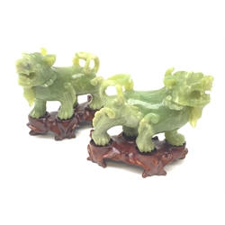 A pair of carved jade dogs of fo, each upon shaped wooden stand, figures H9.5cm. 