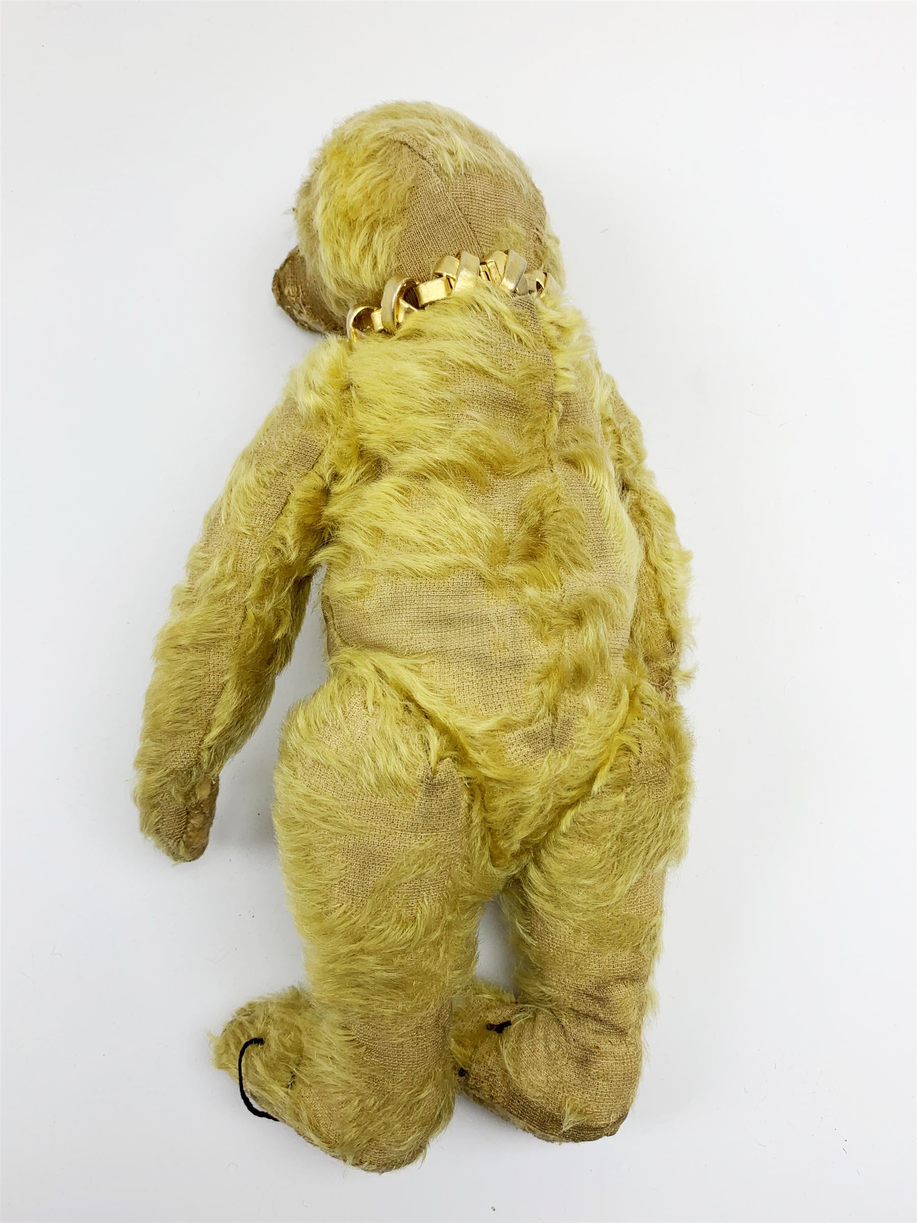 Early 20th century English teddy bear, with wood wool filled body with jointed limbs, felt covered paw pads, five claw stitching to feet and elongated arms with spoon shaped paws H14