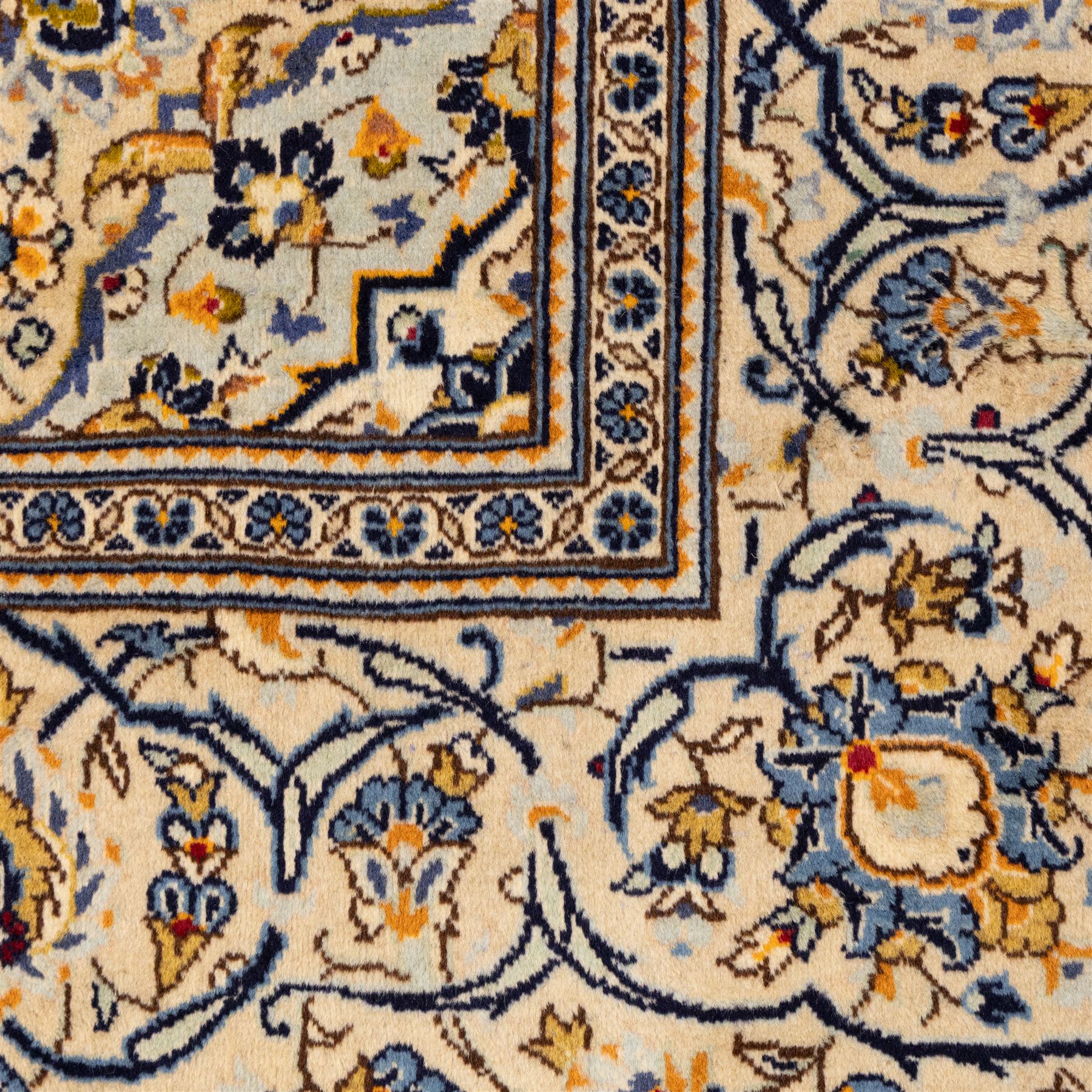 Central Persian Kashan hand-knotted carpet, ivory ground with central stepped floral medallion surrounded by scrolling vine work, palmettes, and stylized blossoms, field enclosed by a multi-border arrangement, wide main border decorated with repeating floral cartouches and foliate motifs, flanked by narrow guard stripes, with cotton fringe ends