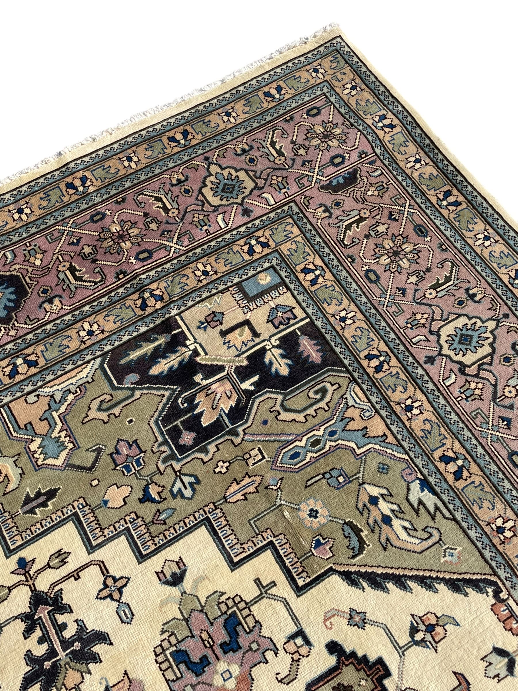 Persian Heriz pale olive and ivory ground carpet, large quatrefoil medallion with palmettes, the surrounding field decorated with trailing leafy branches and stylised plant motifs, peach ground borders with overall floral pattern, within guard stripes 