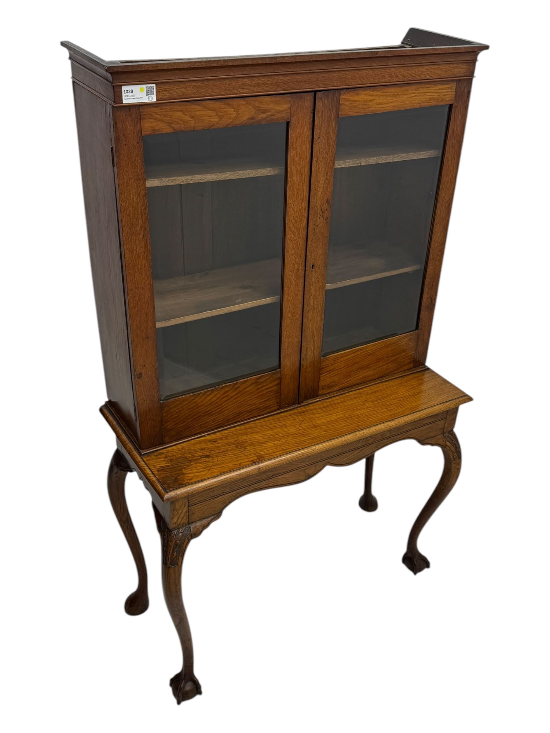 Late 19th century oak display cabinet, rectangular form with a pair of glazed doors enclosing shelves, raised on cabriole supports with carved detailing ending in claw feet