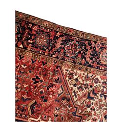 Persian Heriz red ground carpet, large stylised pole medallion surrounded by Pitrak motifs, indigo ground border decorated with stylised flower heads and trailing leafy branches, within floral pattern guard stripes