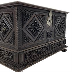 Early 20th century carved hardwood kist or mule chest of small proportions, moulded rectangular hinged lid over foliage carved geometric lozenge panels, the frame carved with chevron banding, fitted with two drawers, the drawer fronts carved with extending leaf motifs over a foliage carved lower moulding, on turned feet