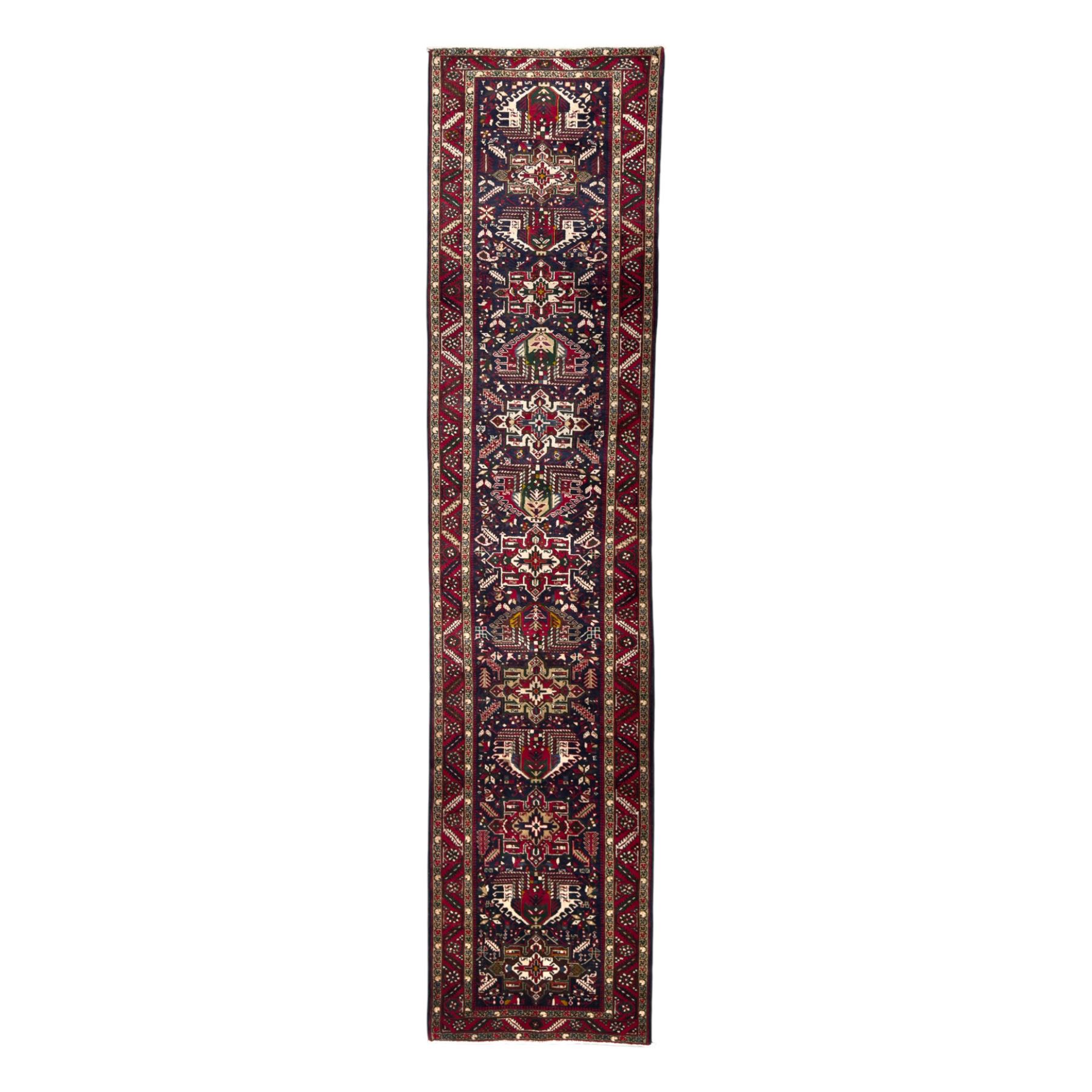 Northwestern Persian Heriz hand-knotted runner, dark indigo field with a series of linked stepped medallions in madder red, ivory, and green, flanked by angular floral motifs, within a madder red border of stylized rosettes and geometric vine motifs 405cm x 95cm