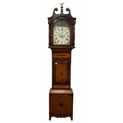 Early 19th century mahogany and oak longcase clock, the hood with scrolled pediment and central finial, stepped arch hood door enclosed by turned columns, inlaid trunk with lobe carved mount, the base inlaid with star motif, shaped apron and bracket feet, Roman enamel dial painted with farming scene, twin train movement striking on bell