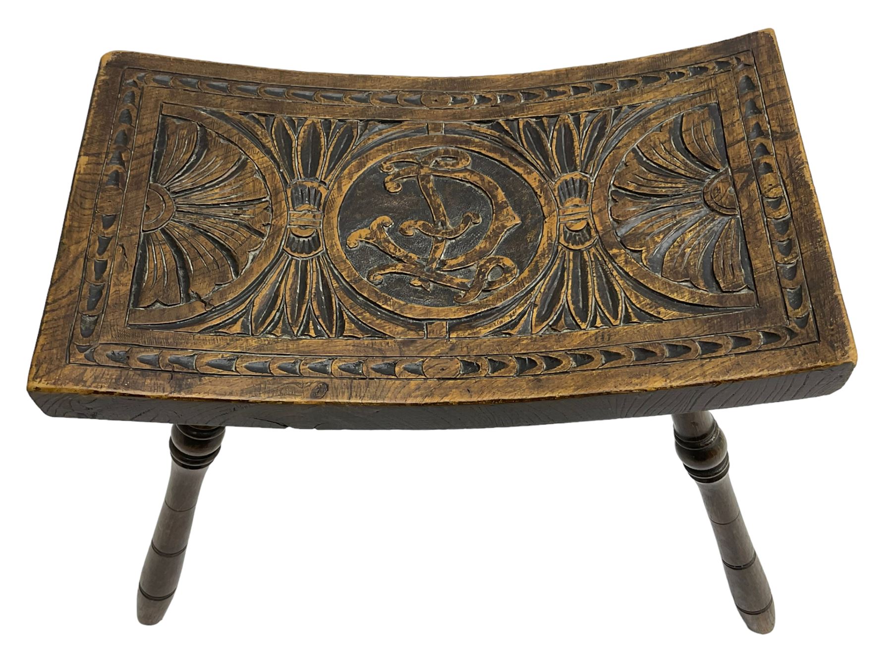 Late 19th century oak stool, rectangular dished top relief carved with floral lunettes and central insignia, on turned splayed supports