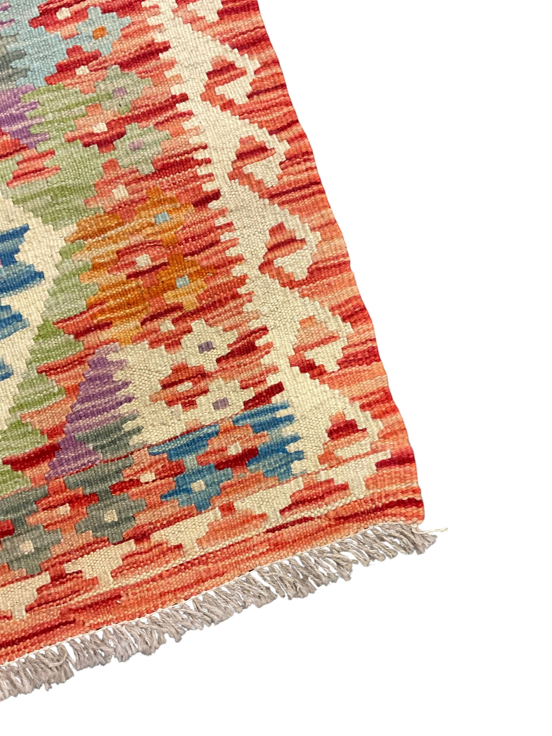 Chobi Kilim red ground and multi-coloured runner, decorated with overall geometric design, trailing lozenges within hooked border