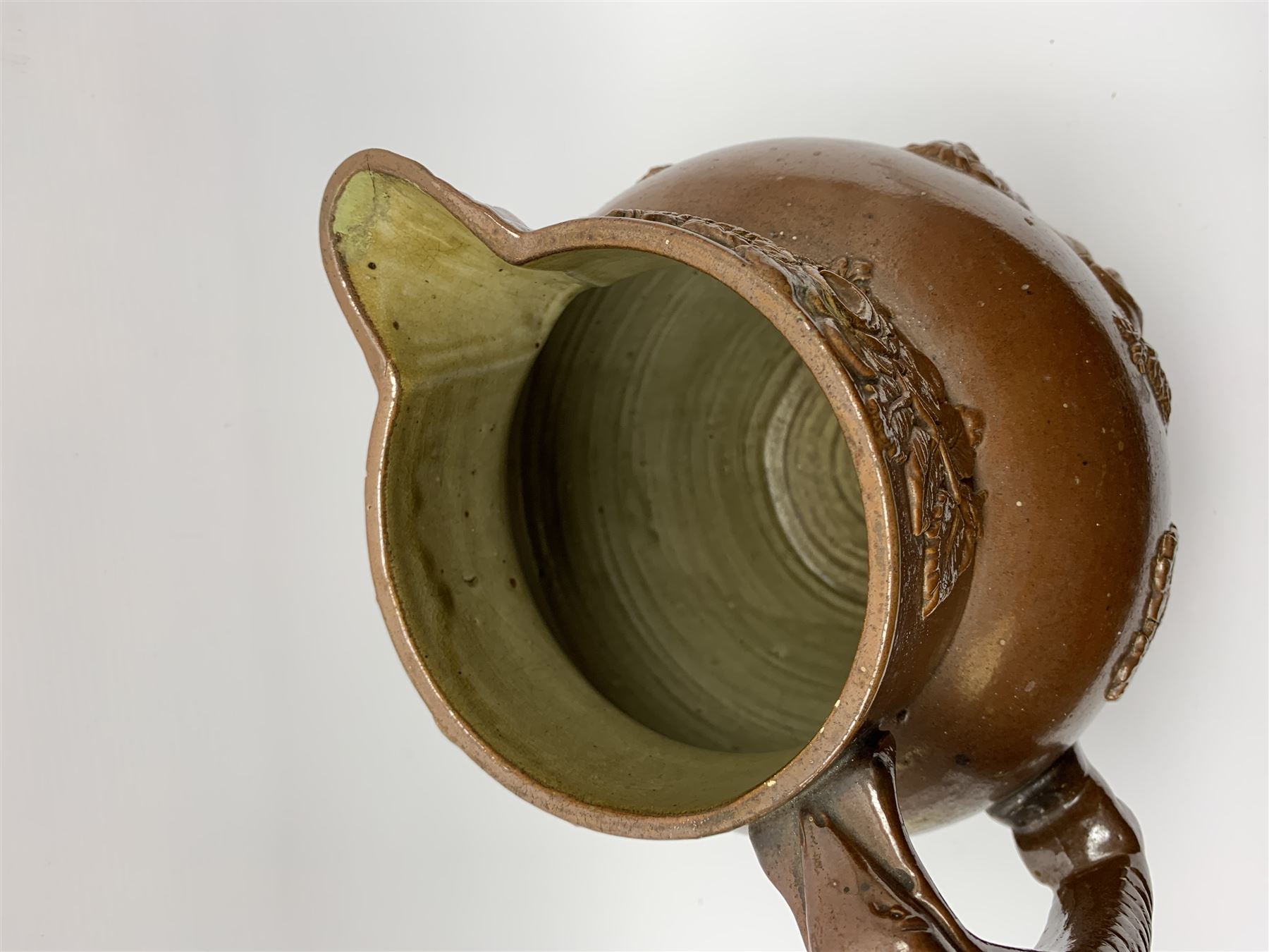 19th century salt glazed stoneware jug, with mask spout and greyhound modelled handle, the body decorated in relief with Royal Coat of Arms flanked by lions, the rim with the flowers of the union, roses, thistles and shamrocks, H26.5cm