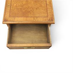 Pair of burr oak bedside tables with campaign brass handles, inlaid and crossbanded top, above four graduating drawers with cockbeaded edges, raised on a plinth base 
