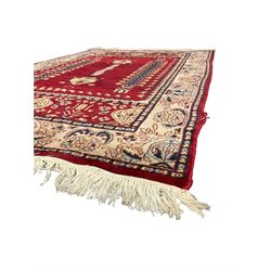Persian red ground rug, the field with extending motifs enclosed by end panels decorated with stylised plant motifs, the main border with repeating pattern 