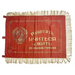 1970s Soviet banner printed in gold on a red ground, roughly translates as 'Transferable Banner - To the winner in the Socialist Competition' and 'Work Study Live by Communism' verso; wreath of wheat ears to either side; tassels on three sides 110 x 155cm