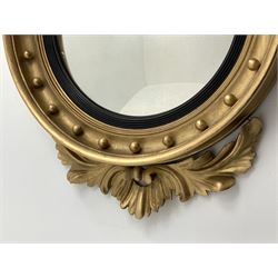 Large Regency carved wood and gesso circular convex mirror, eagle pediment on platform flanked by acanthus leaf scrolls, moulded surround and ebonised slip