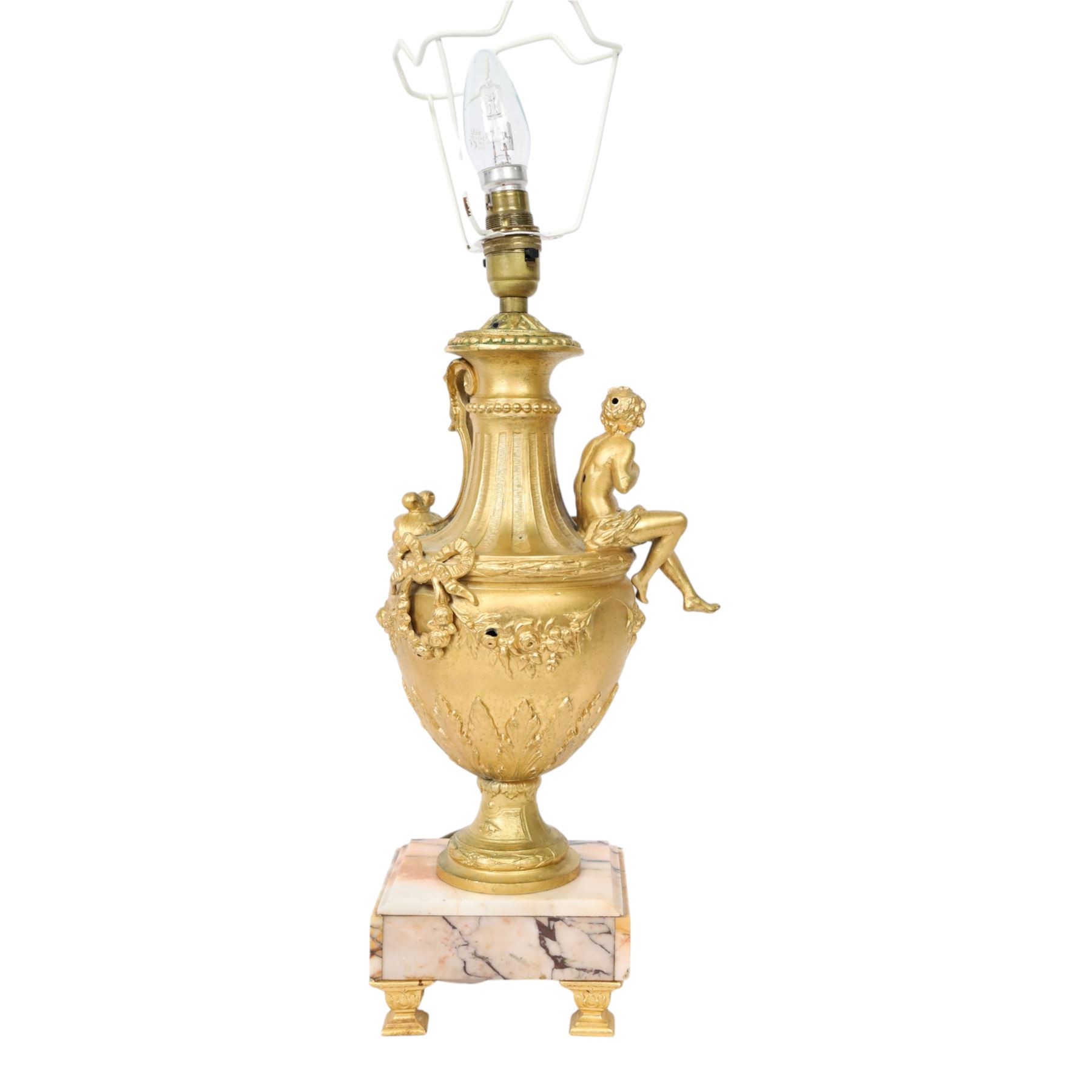 Pair of Rococo style gilt metal table lamps, the urn shaped bodies each with applied figure seated upon shoulder, and female mask to opposite side issuing scroll leading to top of neck, the body cast and applied with stiff leaf detail, and foliate swags and wreaths, upon square pink marble plinths with applied gilt metal mask mounts, and four gilt metal bracket feet, each supported a pleated cream silk closed top lampshade, H63cm