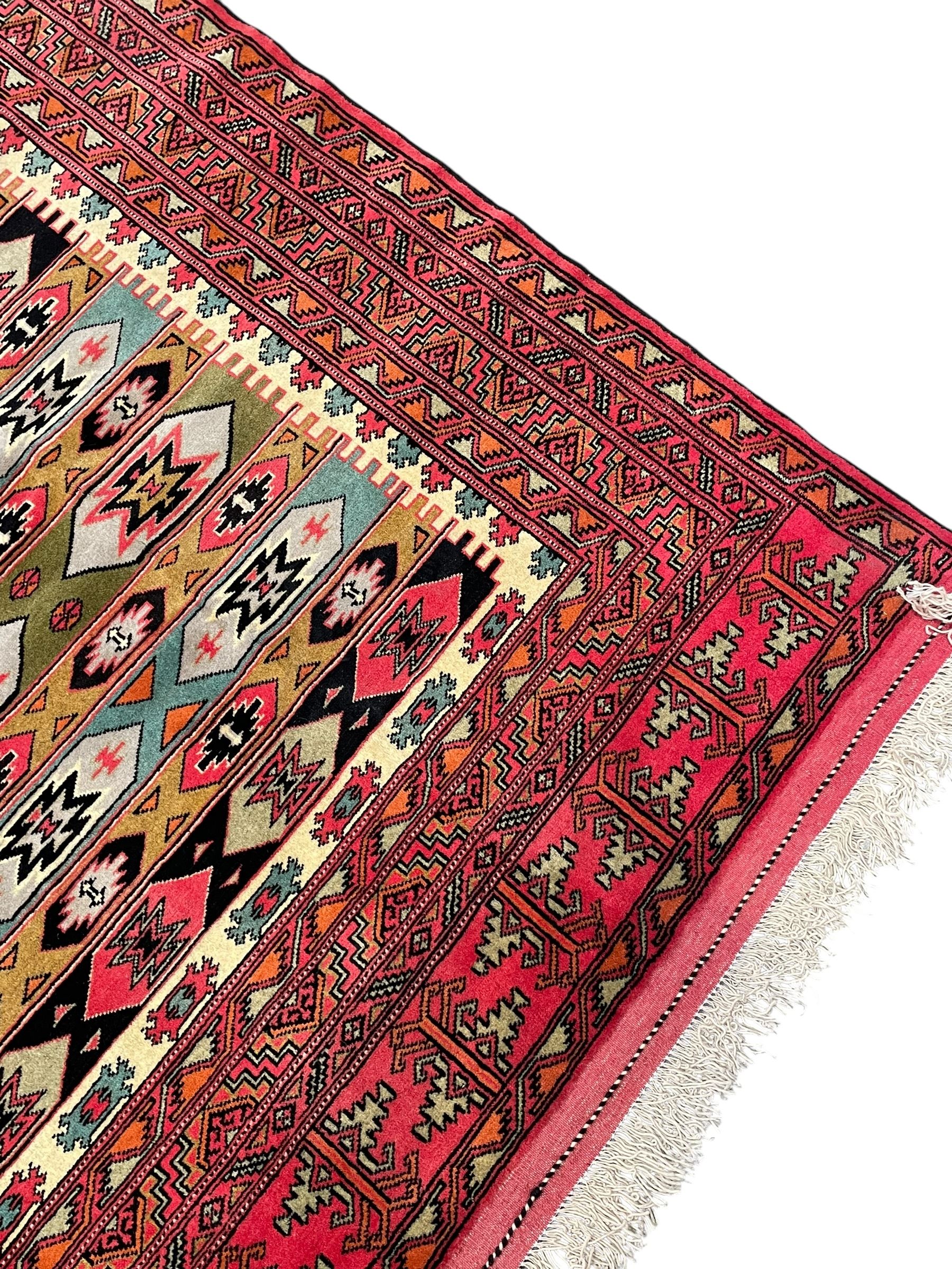 Turkaman red ground rug, the field divided into horizontal rows and decorated with geometric motifs, intricately pattern borders and end panels