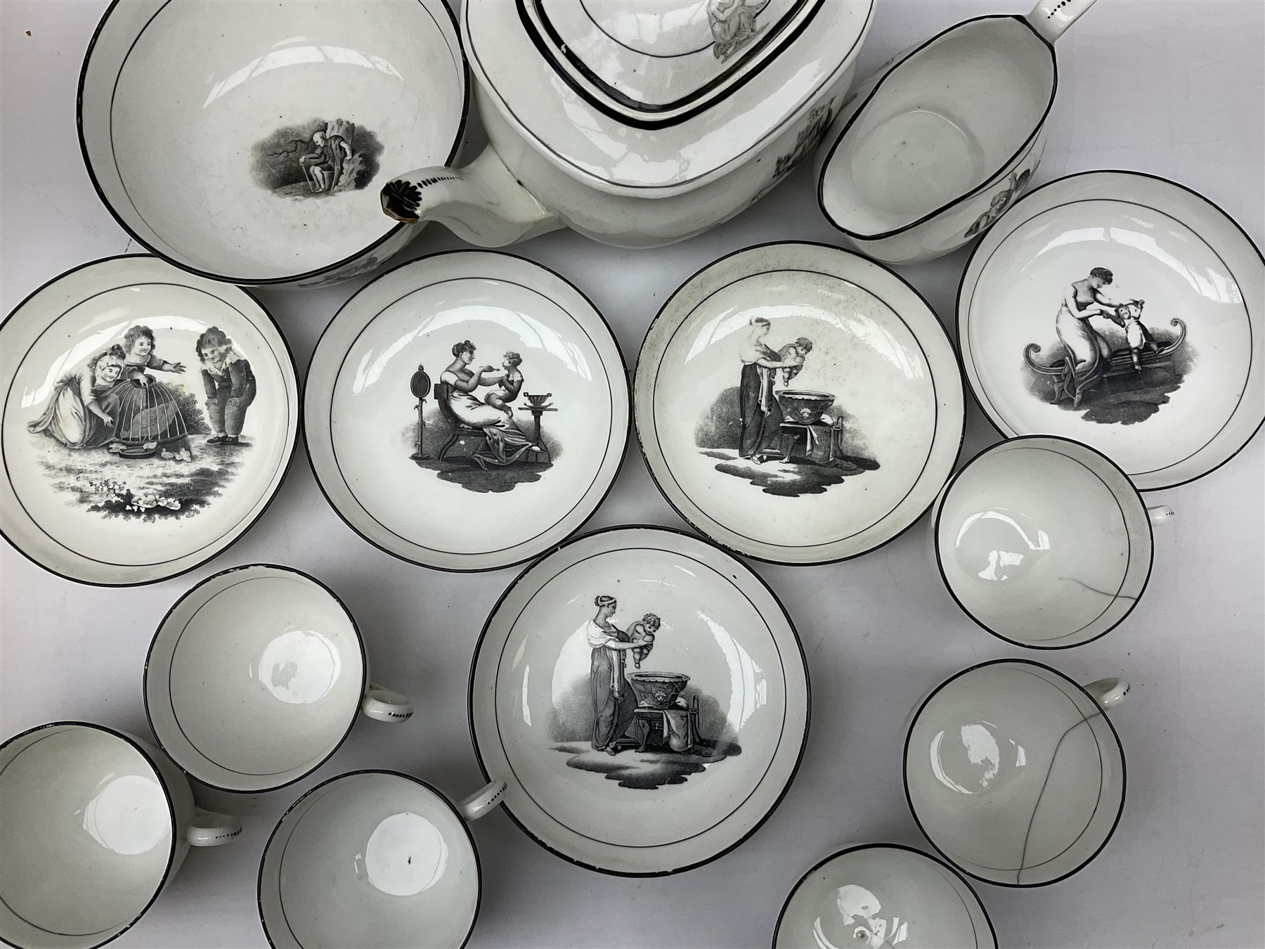 Early 19th century Staffordshire bat printed part tea service, decorated in black after Adam Buck with scenes of mother and child and other varying classical style scenes, within black bands, comprising teapot, slop bowl, jug, seven teacups and five saucers 
