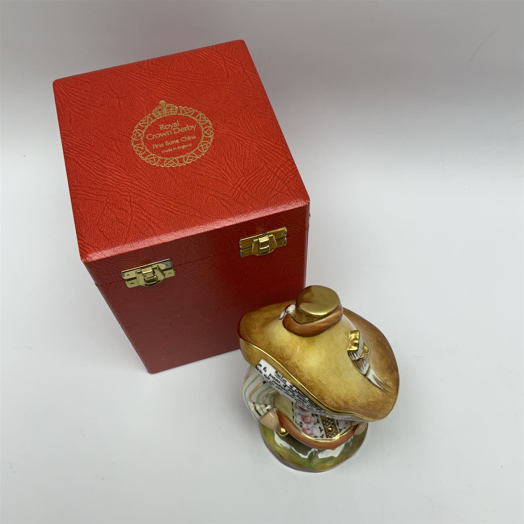 A Royal Crown Derby Mansion House dwarf, dressed in 17th century cavalier costume, with floral waistcoat and hate detailed Auction of Elegant Household Furniture and Effects, H18cm, with printed mark beneath and signed J.Aston, with makers box. 