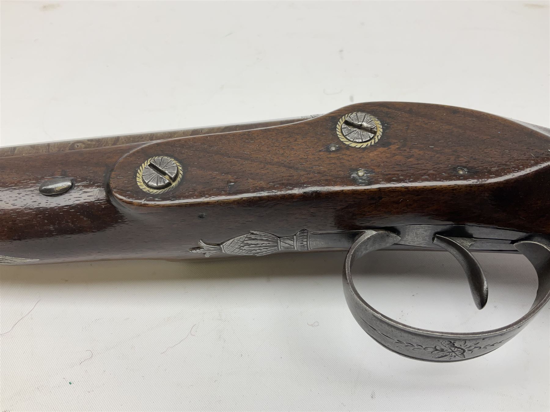 Early 19th century flintlock 16-bore overcoat/duelling pistol by William Bond Lombard Street London, the 23cm octagonal brown stub twist damascus barrel with small foresight, two barrel pins and ram rod under, inscribed Lombard Street London to the top and W. Bond to the action, full walnut stock with lightly engraved steel furniture, pineapple finial and escutcheon, half cock facility L39cm; loose mounted on later mahogany display stand with trade label