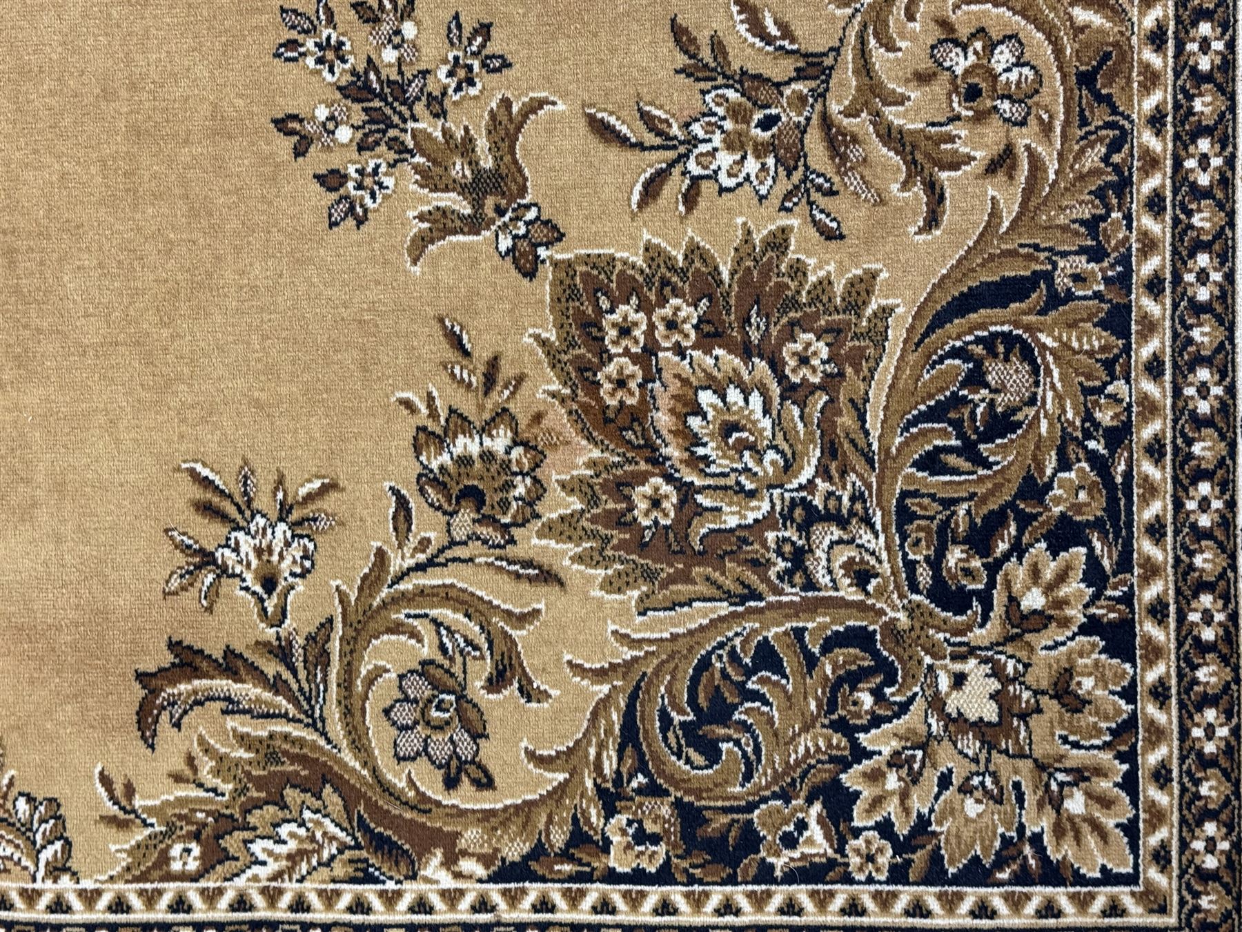 Persian design golden beige ground rug, the field with symmetrical scrolling foliate and floral designs, central floral medallion, bordered by a multi-layered band with floral and vine patterns in contrasting beige and dark brown tones
