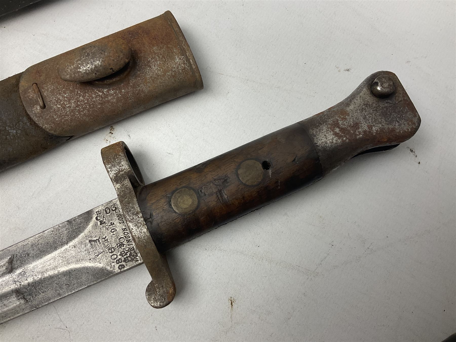 British No 7 MKI knife bayonet with 20cm single edged fullered clipped point blade;  blackened steel, large muzzle ring cross-guard; blackened swivelling pommel marked 'F5H'; red Tufnol composite grips; in blackened steel scabbard L33cm overall; British Pattern 1888 bayonet with scabbard; and German Ersatz bayonet with scabbard (3)