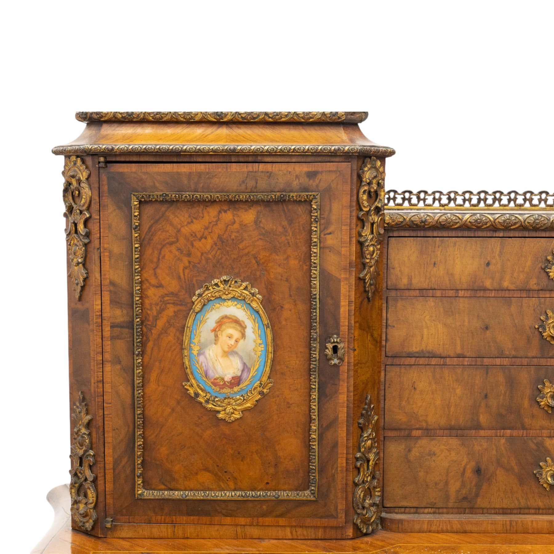 Late 19th-century Louis XV revival gilt bronze mounted and walnut Bonheur-de-Jour, rectangular-shaped serpentine form, with gilt bronze beading, frieze with two blind drawers and gilt bronze handles, centre drawer with large central serves style porcelain plaque, the elevated section with brass gallery above panelled cupboard doors also with serves style porcelain plaques and gilt bronze mounts, interior with single shelf, central section with four drawers each with gilt bronze handles, raised on slender cabriole legs fitted with gilt bronze rococo style masks and sabots