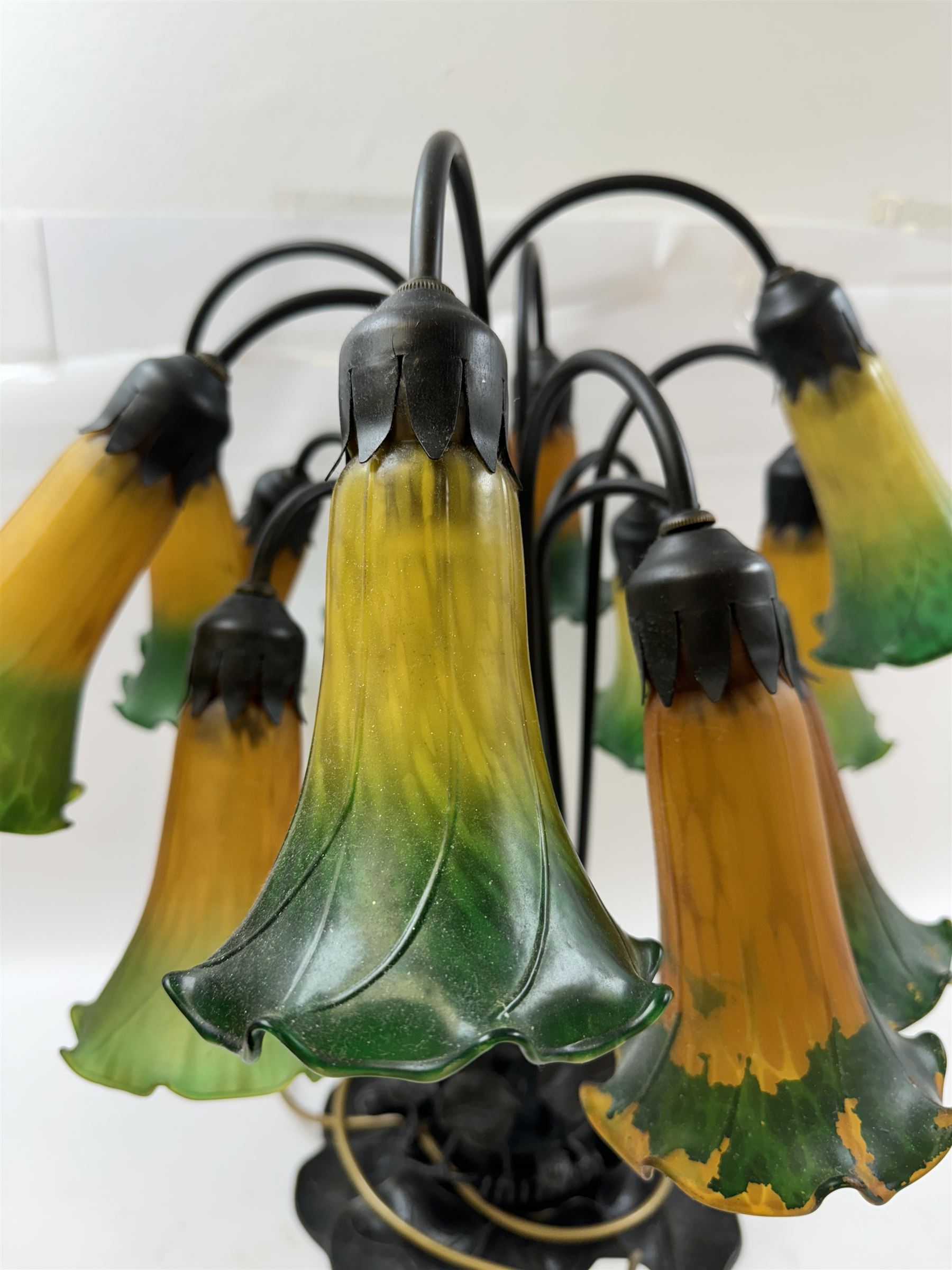 Art Nouveau Tiffany style table lamp, the bronzed base modelled as lily pads leading to tendrils and twelve branches supporting green and yellow glass lily flower shades, H53cm