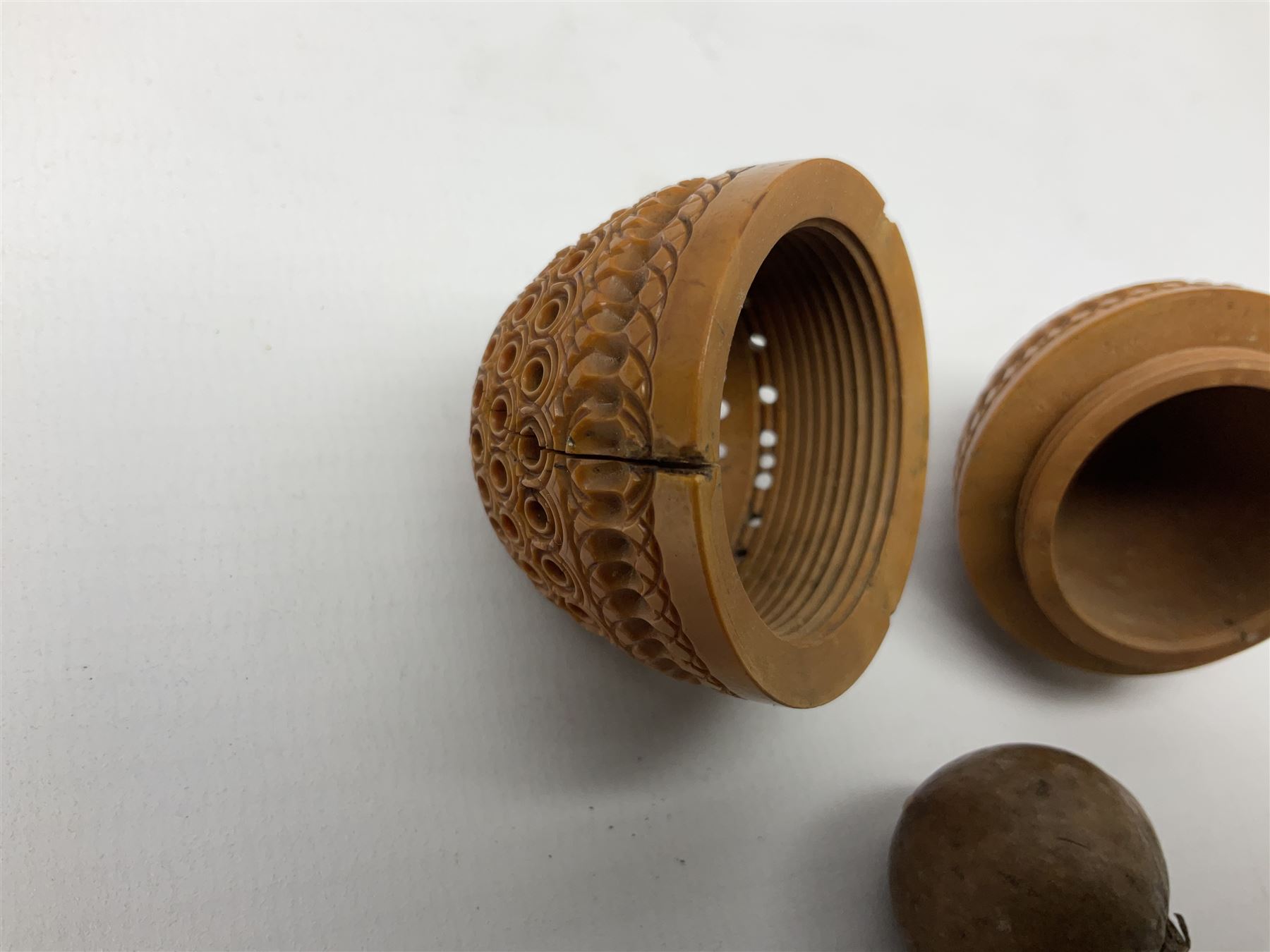 Three 19th century coquilla nut pomanders or flea catchers, each of egg shaped form with carved and pierced decoration and screw threaded join, largest example 6cm