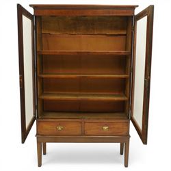 19th century mahogany enclosed bookcase on stand, projecting cornice and banded frieze over two glazed doors enclosing four adjustable shelves, fitted with two drawers to base, on square tapering supports