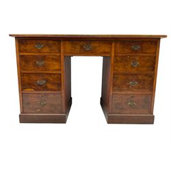 Late 19th to early 20th century walnut pedestal desk, rectangular top inset with red tooled leather writing surface, over a central frieze drawer flanked by two pedestals, each fitted with four graduated drawers with brass escutcheons and drop handles, the whole raised on a plinth base