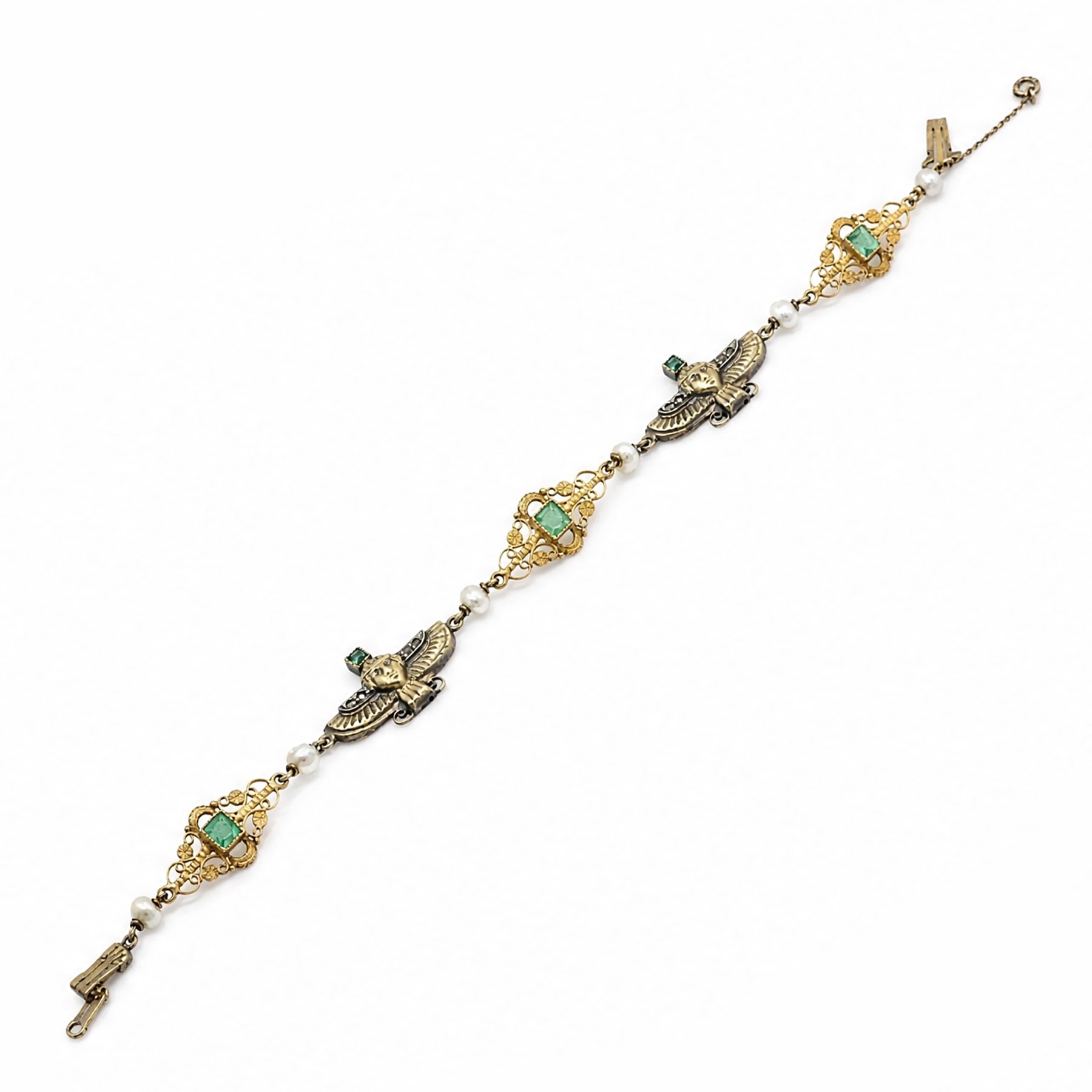 Early 20th century French 18ct gold Egyptian Revival bracelet, three winged sphinx motif panels, each set with a square cut emerald and four rose cut diamonds, spaced by six white / cream pearls and three scrolling openwork links, each centred with a square cut emerald, French assay marks