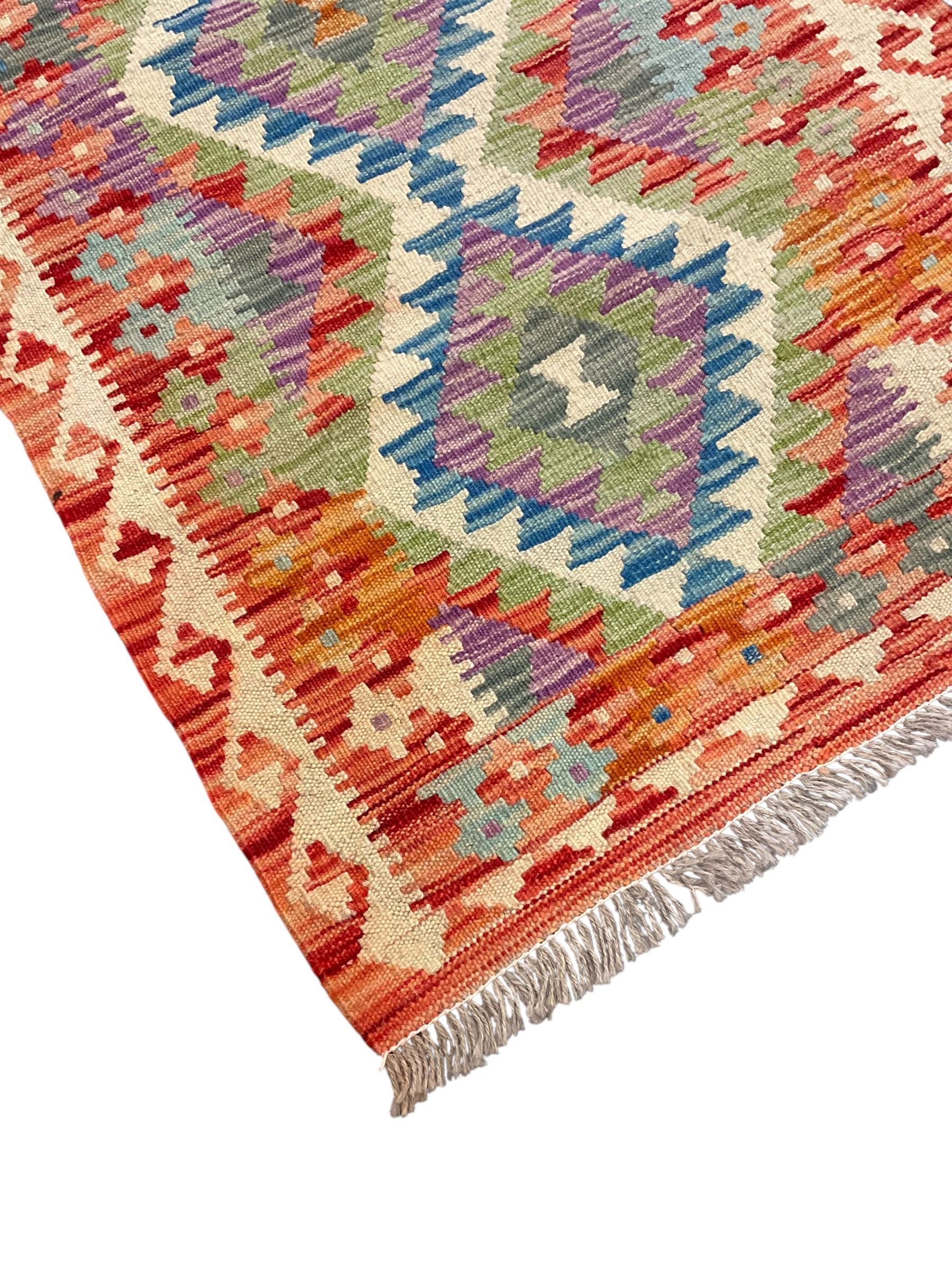 Chobi Kilim red ground and multi-coloured runner, decorated with overall geometric design, trailing lozenges within hooked border
