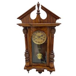 German early 20th century wall clock in a mahogany case with an architectural pediment and turned finial, with applied carving and pendant finials, fully glazed door with a visible gridiron pendulum, eight-day spring driven striking movement striking the hours on a gong, dial with Roman numerals to the chapter and a gilt repoussé centre.   


