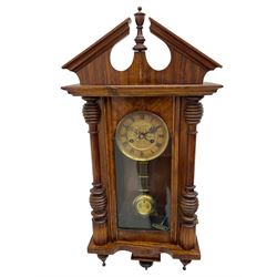 German early 20th century wall clock in a mahogany case with an architectural pediment and turned finial, with applied carving and pendant finials, fully glazed door with a visible gridiron pendulum, eight-day spring driven striking movement striking the hours on a gong, dial with Roman numerals to the chapter and a gilt repoussé centre.   

