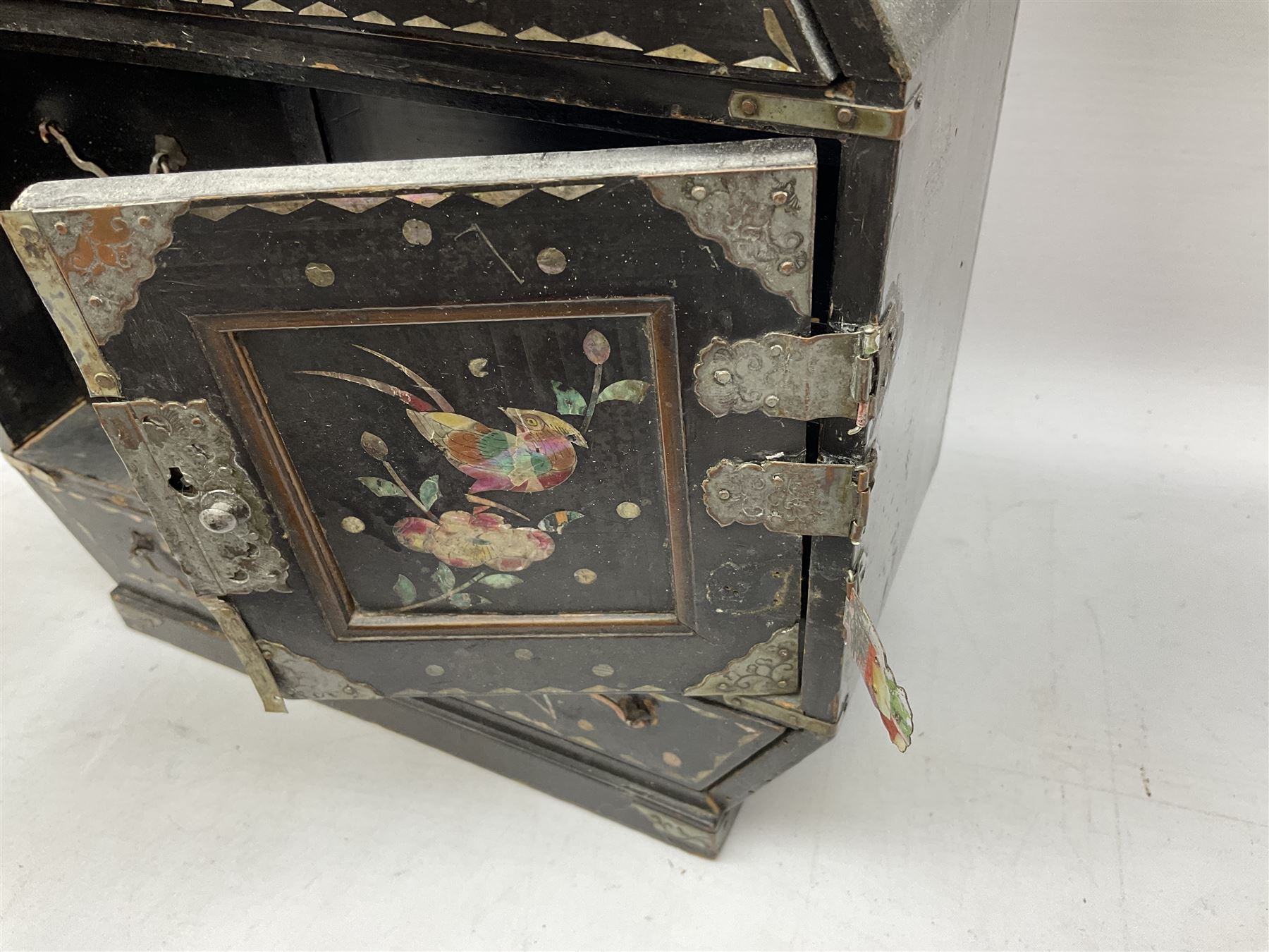  Late 19th / early 20th century Japanese lacquered table top cabinet, heavily decorated with mother of pearl inlay depicting blossoming branches, flowers and birds, the two hinged doors between longer drawers opening to reveal interior fitted with four short drawers, with lift up hinged canted lid, H28cm D9.5cm W23cm, together with mother of pearl inlaid miniature folding screen, dish decorated with walking figures with crimped edge, boxes decorated with flowers, birds and gilt etc