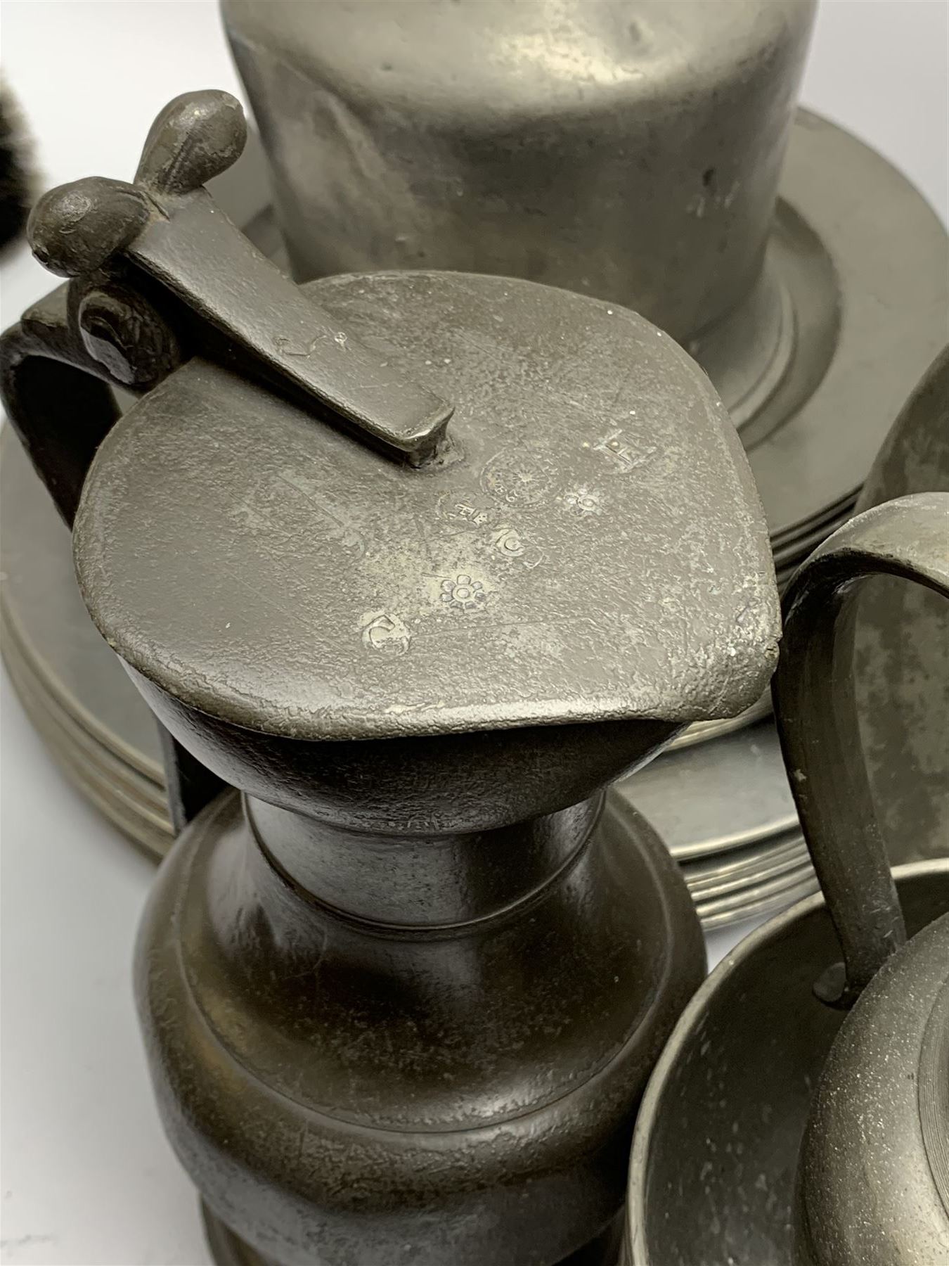Collection of 18th and 19th century pewter, comprising two chargers, eight large plates, twenty six smaller plates, two bowls, three lidded measures, two jugs, tappit hen, and tankard, the plates with various marks and touch marks, including pseudo 'hallmarks', largest charger 37cm, large plates D30cm, smaller plates D24.5cm, tappit hen H26.5cm