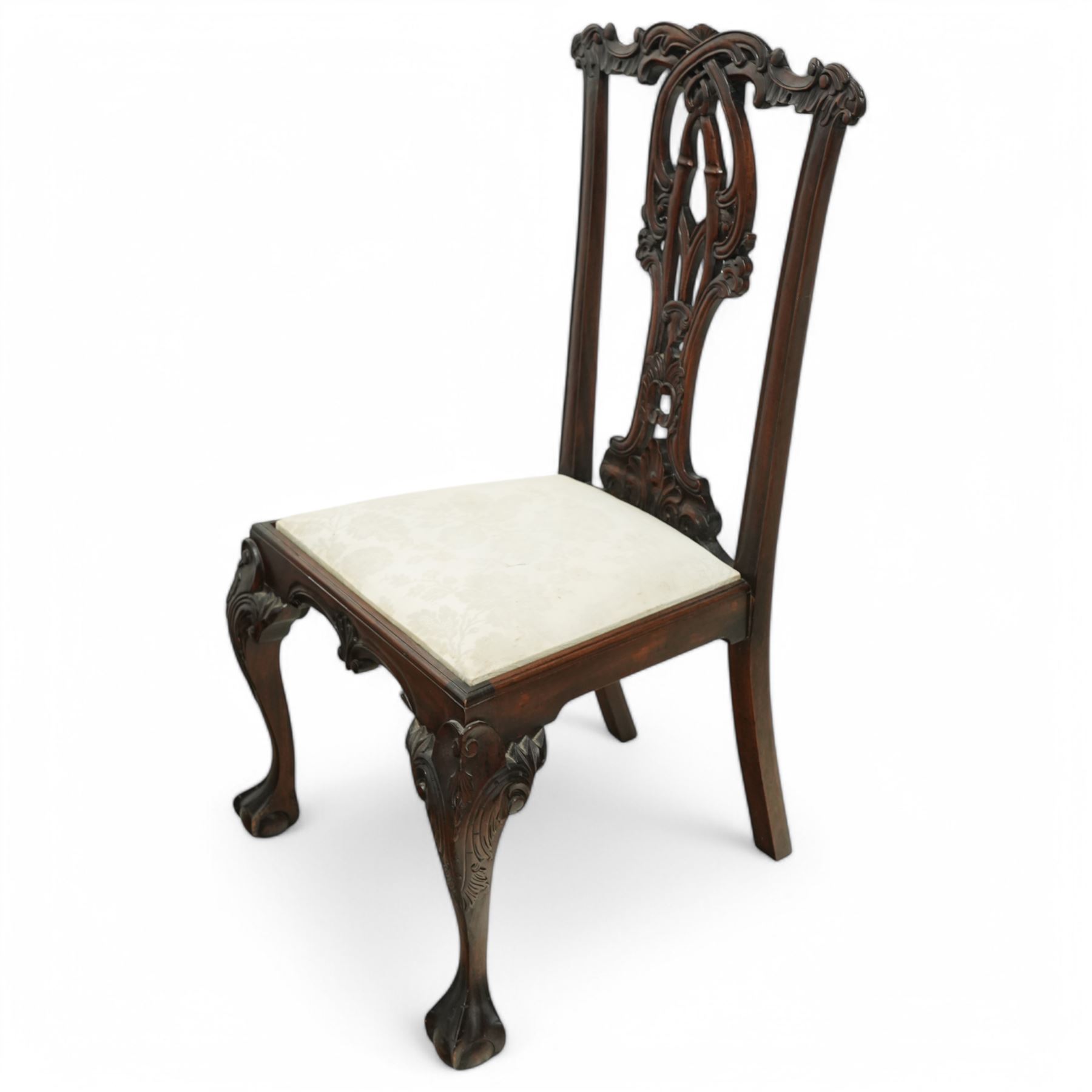 Chippendale revival mahogany dining chairs, set of six including a pair of carvers, the backs with intricately carved pierced splats beneath serpentine cresting rails, on acanthus carved cabriole front supports terminating in claw and ball feet, with cream upholstered drop-in seats
