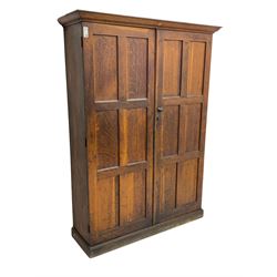 The North of England School Furnishing Company Limited Darlington - early 20th century oak school cupboard, projecting moulded cornice over two panelled doors, fitted with shelves, on chamfered plinth base 
