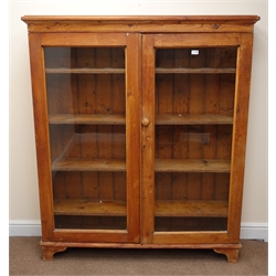  Early 20th century pitch pine bookcase, two glazed doors enclosing four shelves, bracket supports, W133cm, H155cm, D30cm  