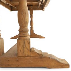 Traditional oak refectory dining table, fitted with draw leaves to either end extending to 257cm, on twin turned and block supports united by a stretcher, terminating in shaped trestle feet