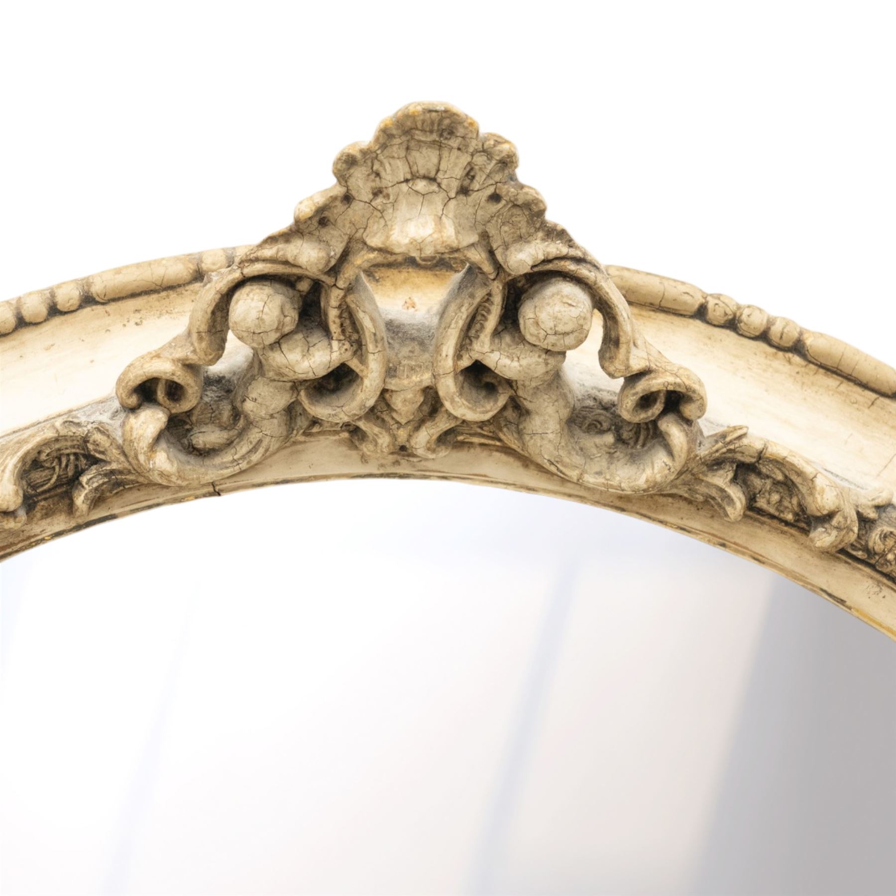 Early 20th century cream and parcel-gilt oval wall mirror with mer-putti pediment